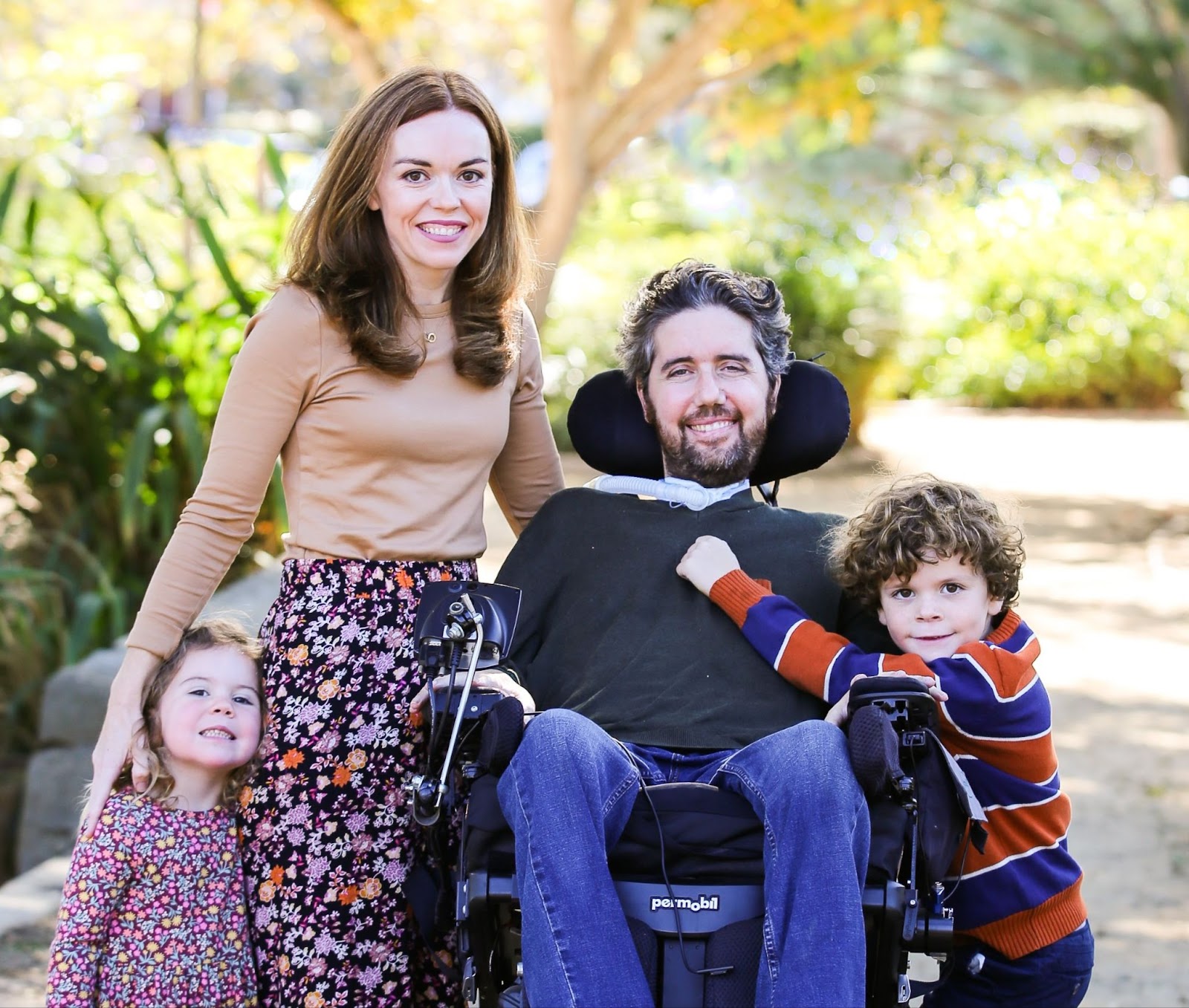 Image of Ady in his wheelchair with his wife Rachael and his chlidren, Willow and Carl