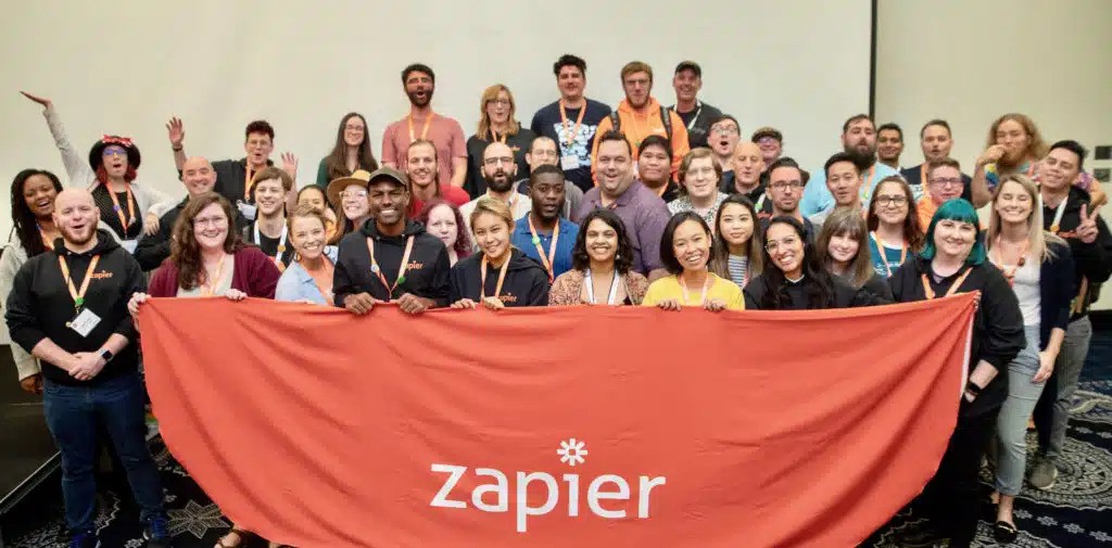 Zapier employees holding a Zapier tapestry