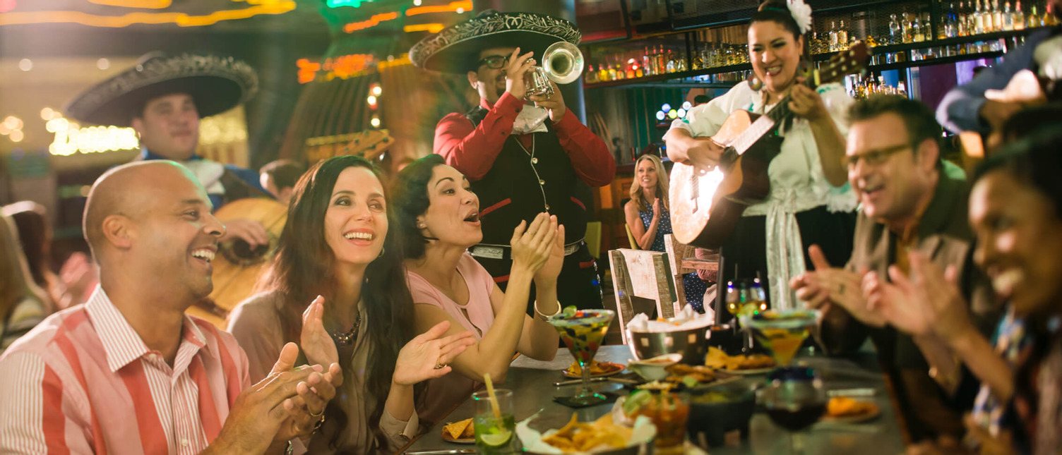 A group of women clap along to a mariachi at Antojitos