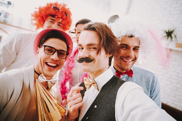 Photo smile gay guys in bow ties taking selfie on phone at party.