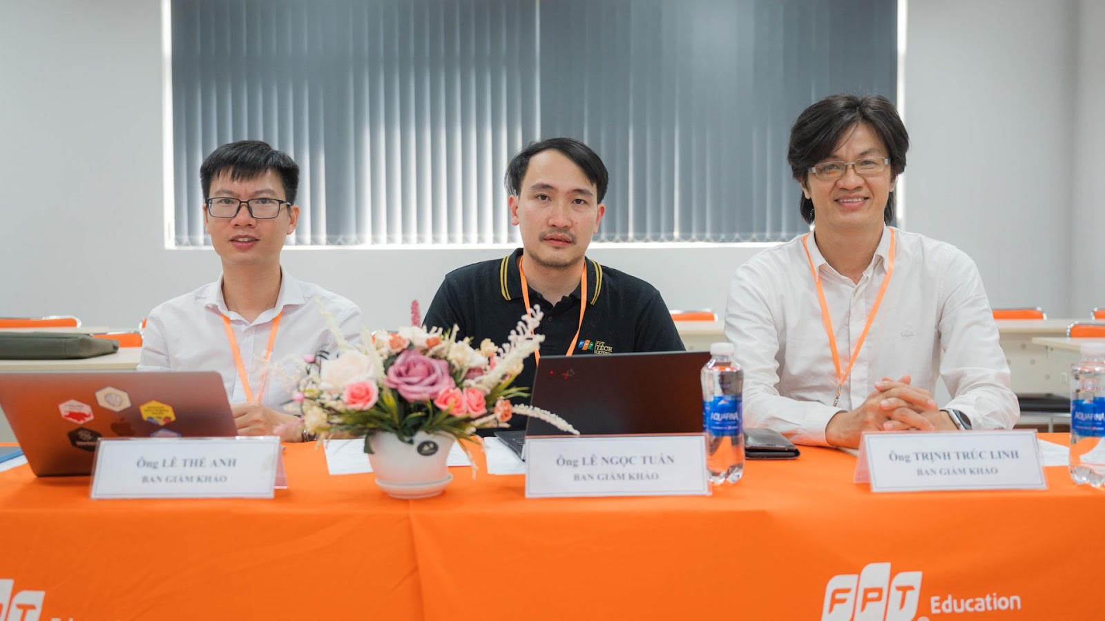 A group of men sitting at a table with orange tableclothDescription automatically generated