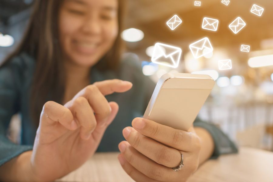 A happy person using a smartphone with floating email icons