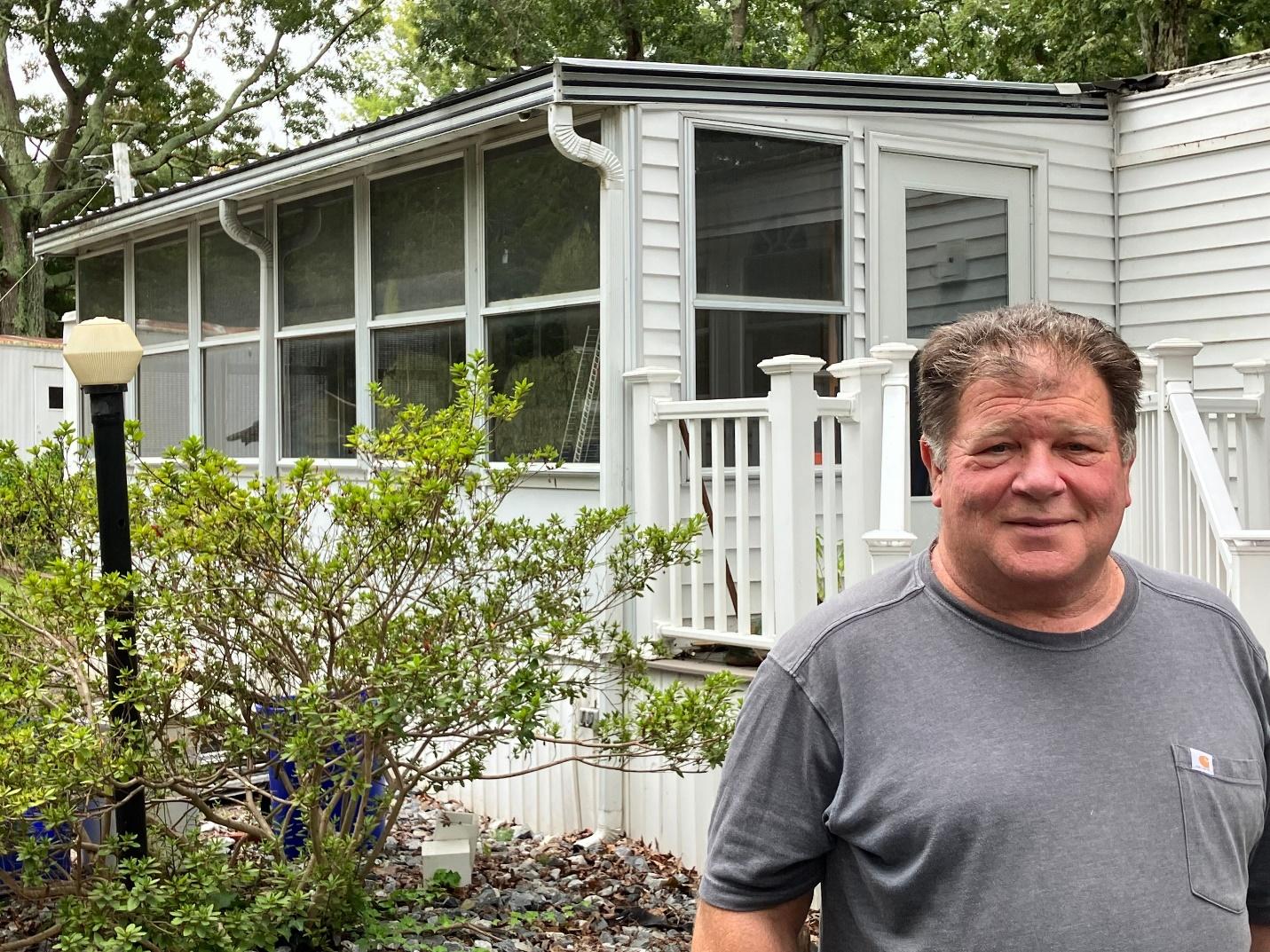 A person standing in front of a white house

Description automatically generated