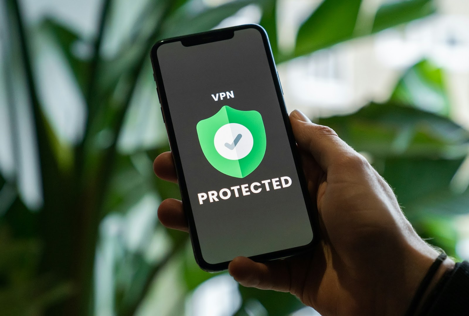 A person holding a smartphone with the word on the screen 'VPN Protected'