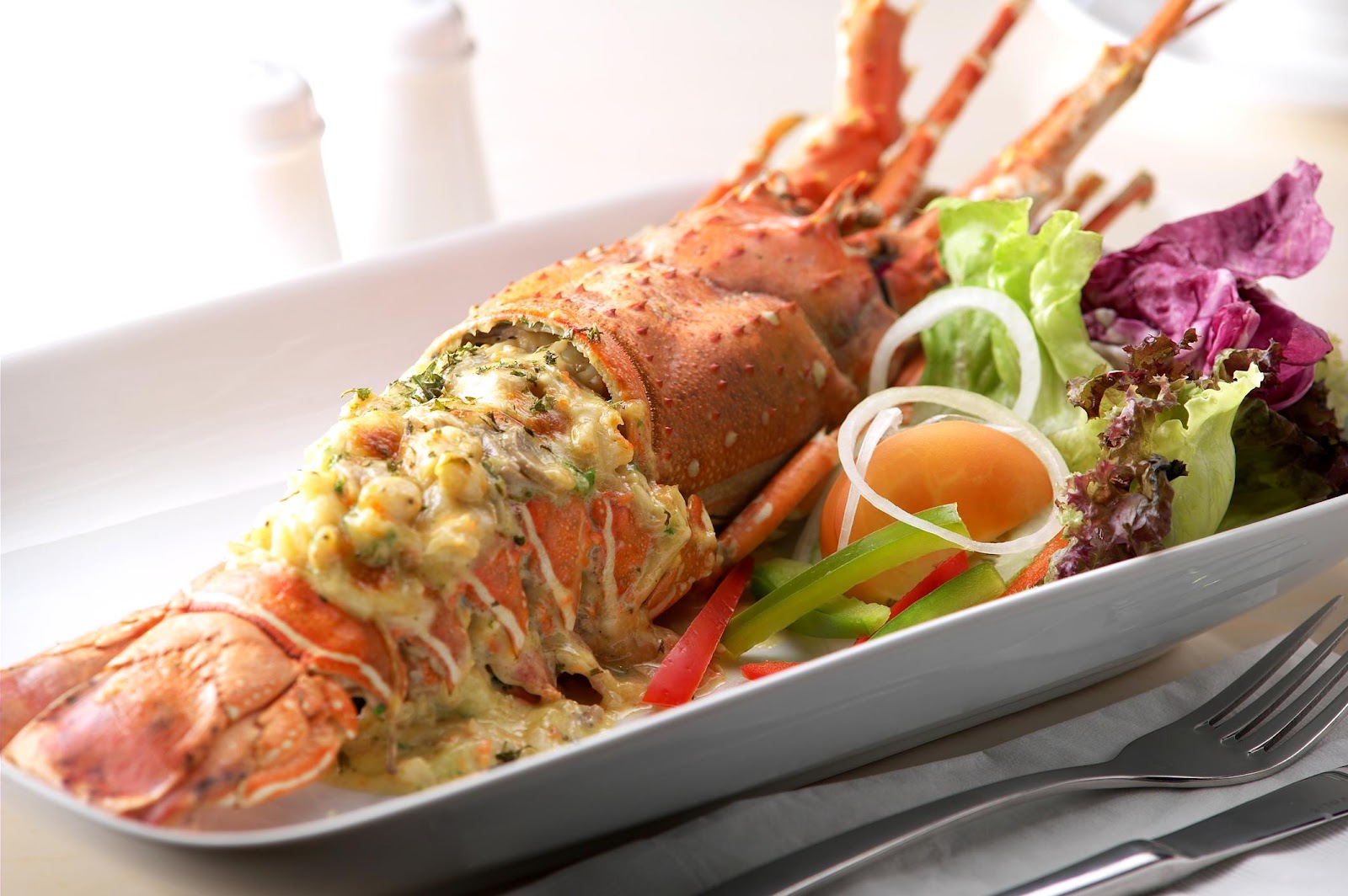A lobster with vegetables on a plate

Description automatically generated