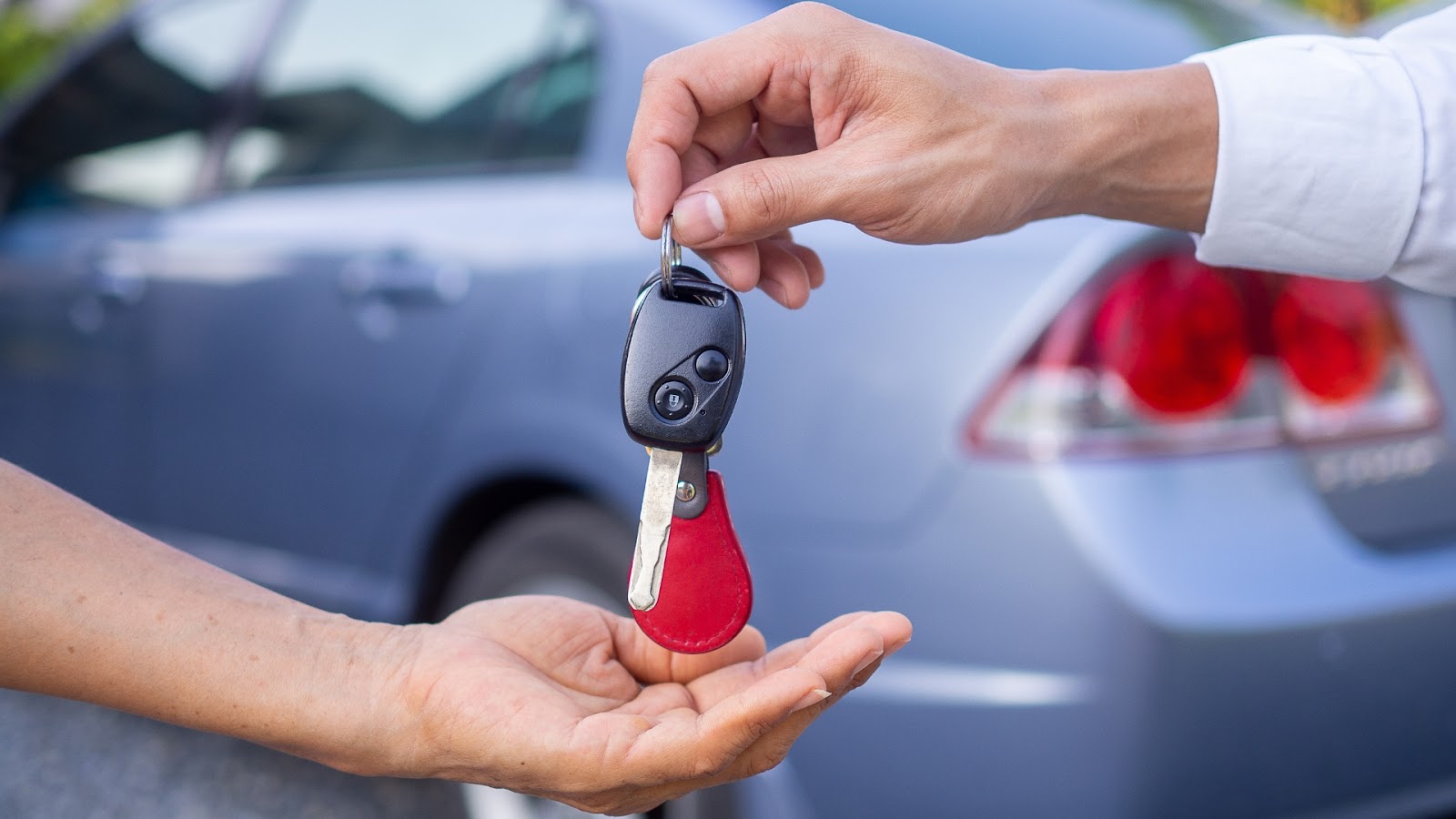 A new car key replacement being handed to a car owner