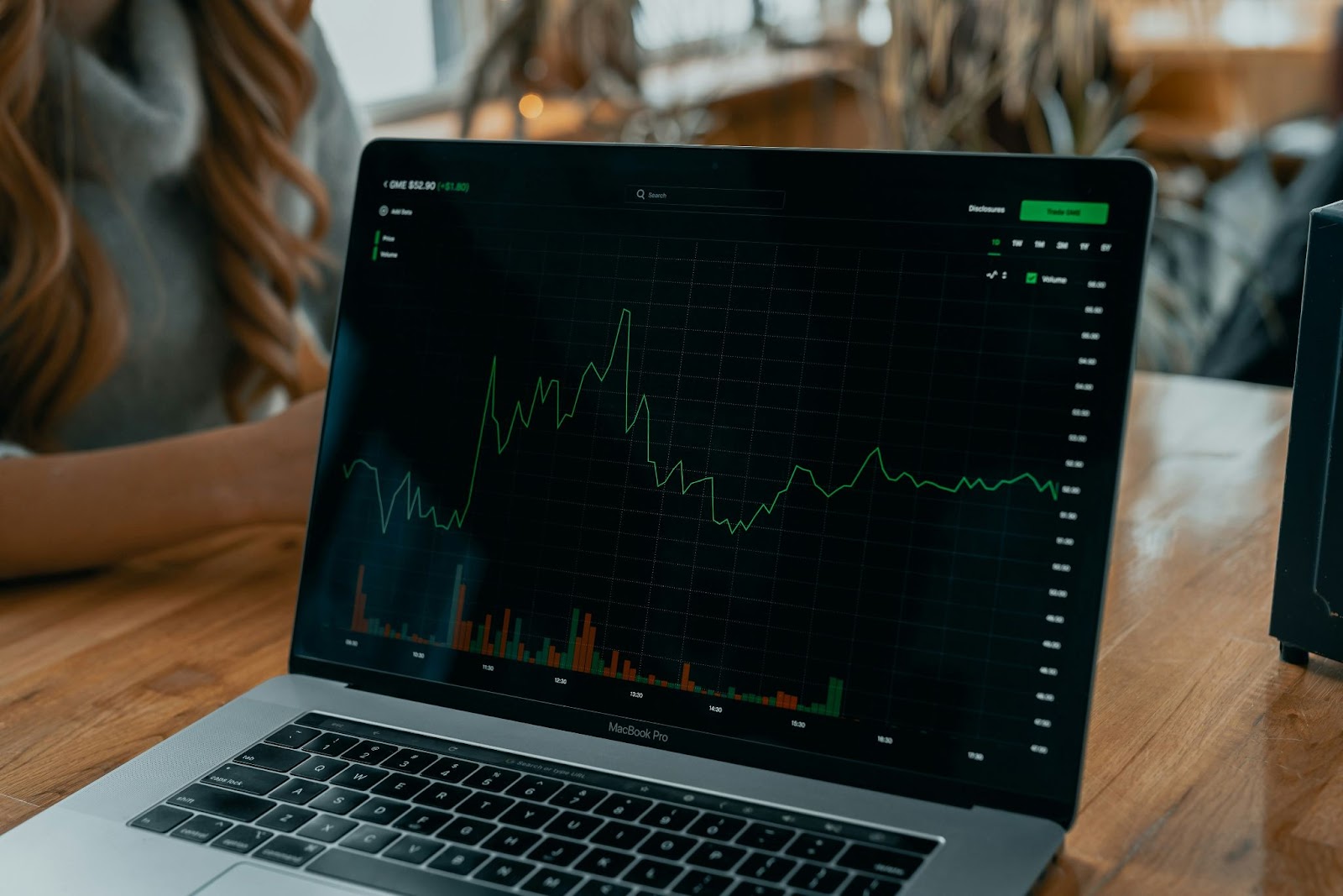 A laptop displaying a rising stock market graph on its screen