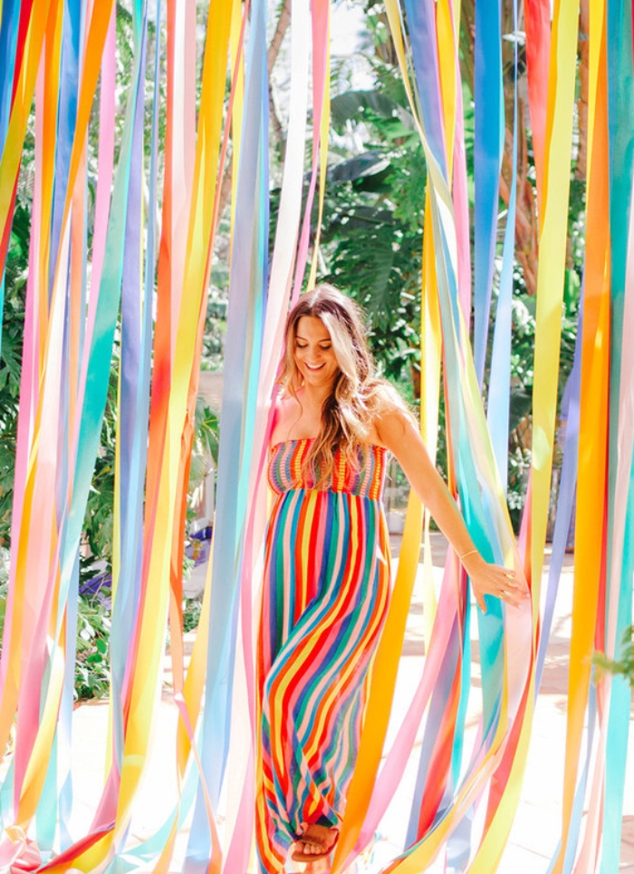 pregnant woman in rainbow dress in front of streamers
