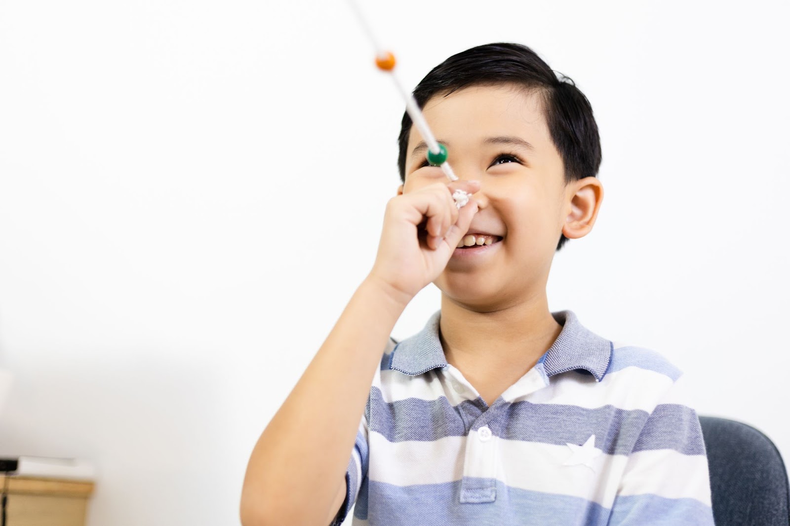 A smiling young boy performing a string exercise in vision therapy to improve binocular vision.