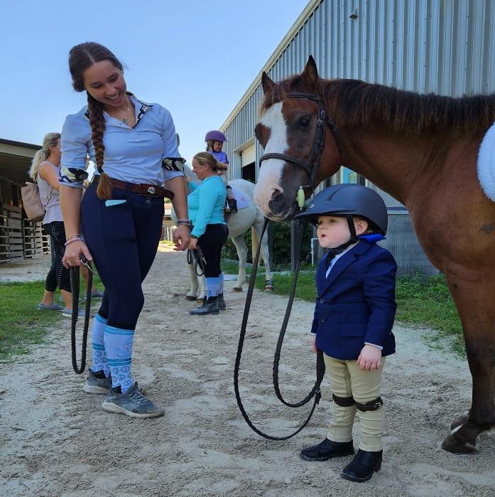 A person and a child standing next to a horse

Description automatically generated