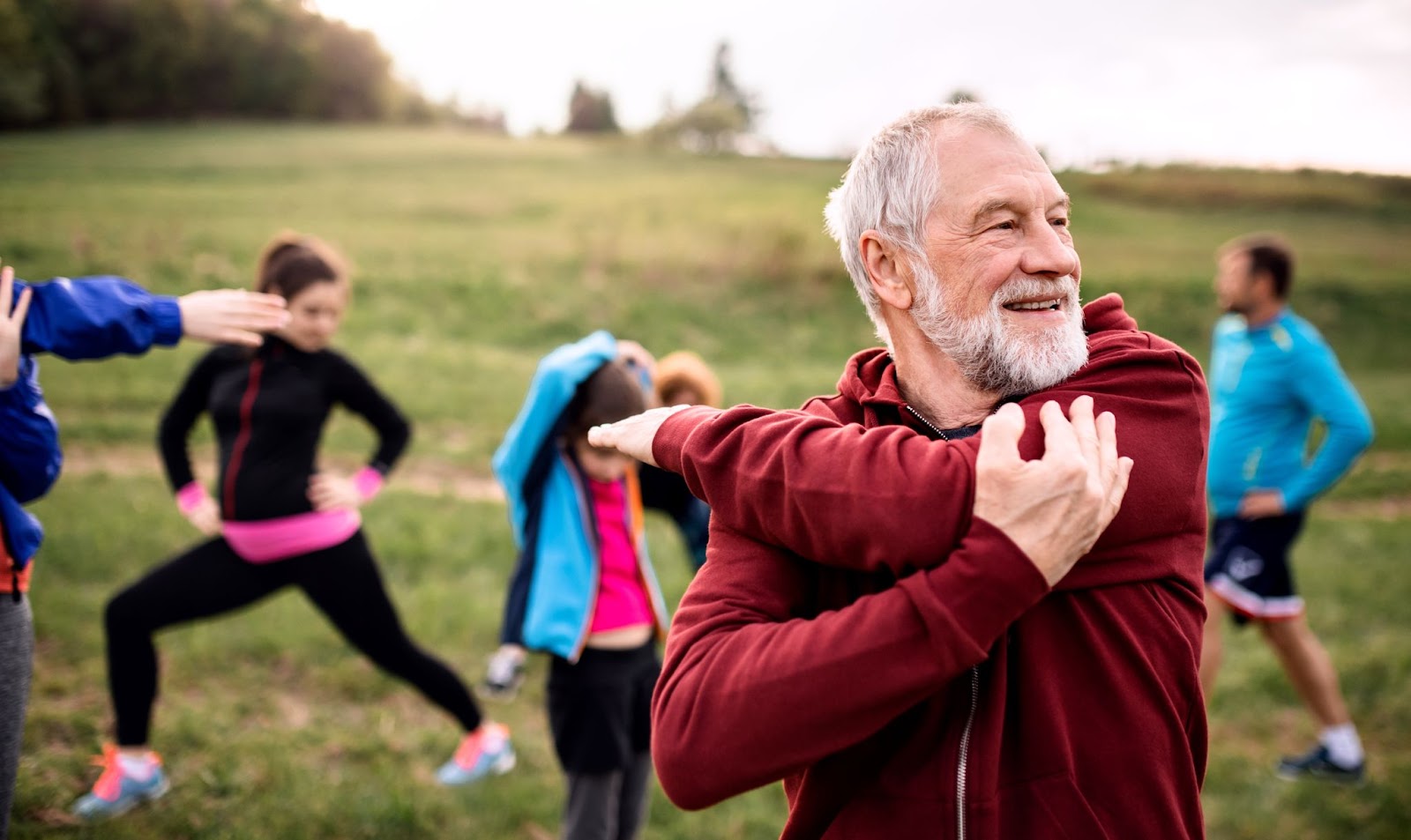 an older man is stretching with a group of fellow seniors to support and maintain a healthy lifestyle.