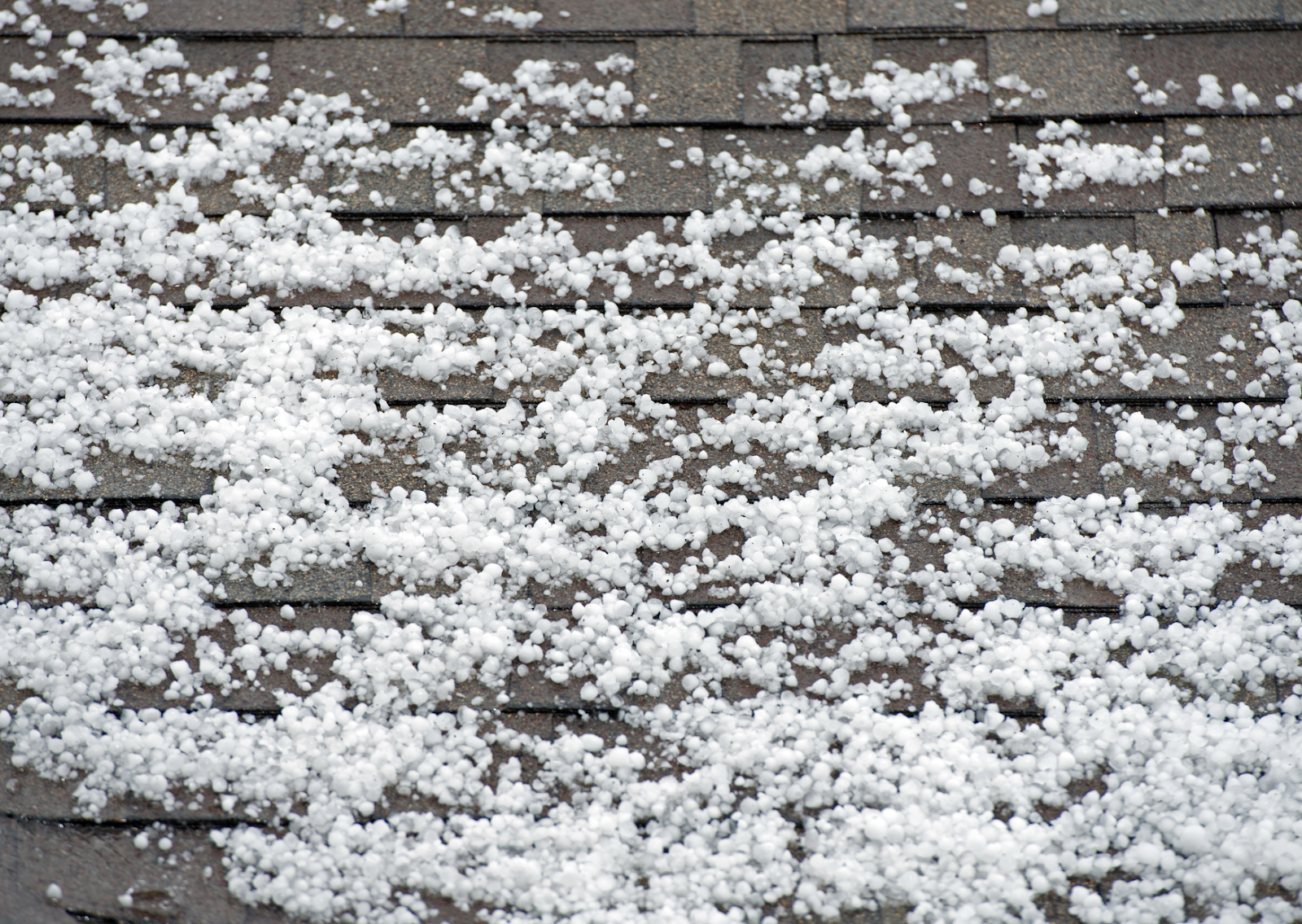 Hailstones scattered across a roof, illustrating the aftermath of severe weather and the potential for a hail-damaged roof.