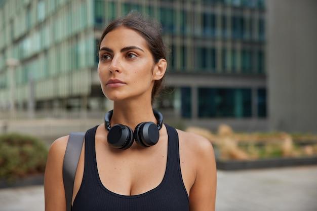 woman thinks over personal training plans dreams to become new qualified dressed in sportsclothes practices yoga or pilates walks to fitness centre or health club stands in downtown