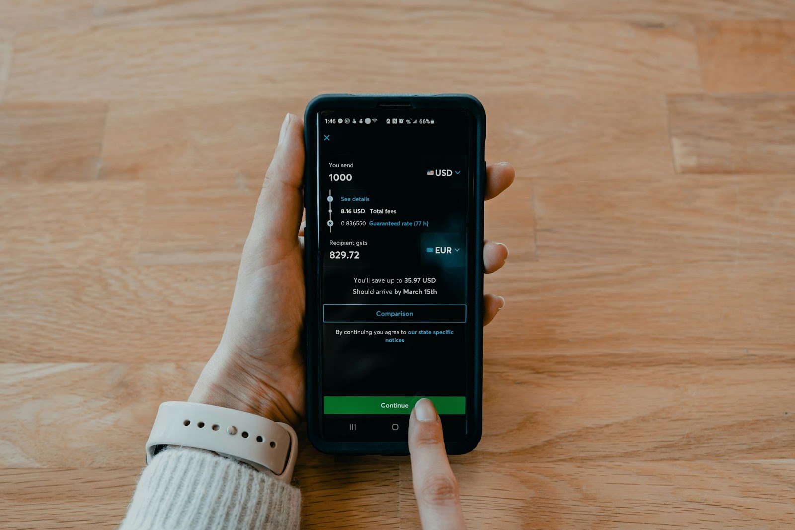 a person holding a smartphone with the screen displays a transaction where the user is sending $1000