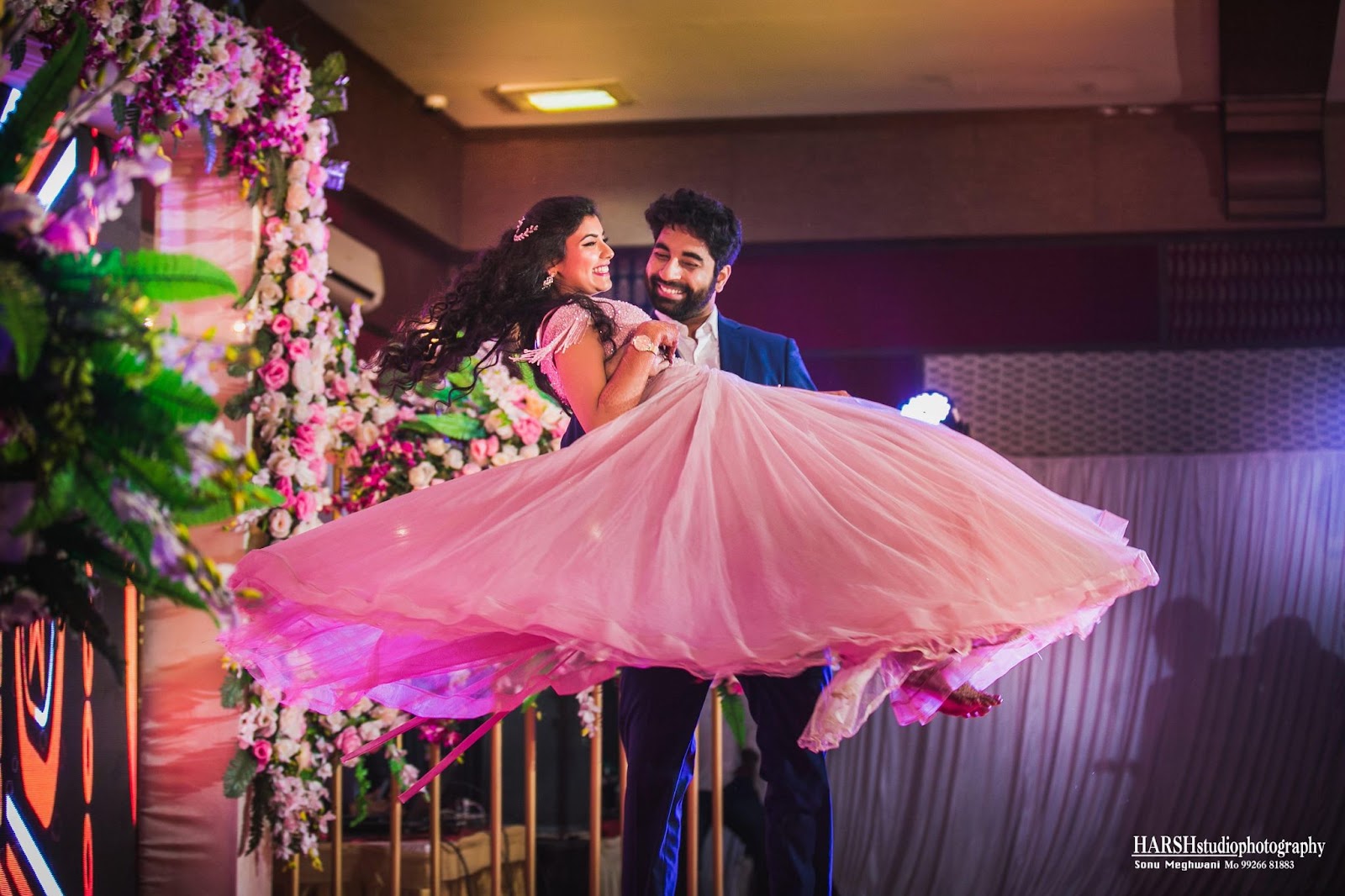 Capture at the sangeet function in Indore, the groom lifting the bride in his arms. Photo by Harsh Studio Photography in 2024. Known for their expertise, capturing cherished wedding moments with creativity and precision