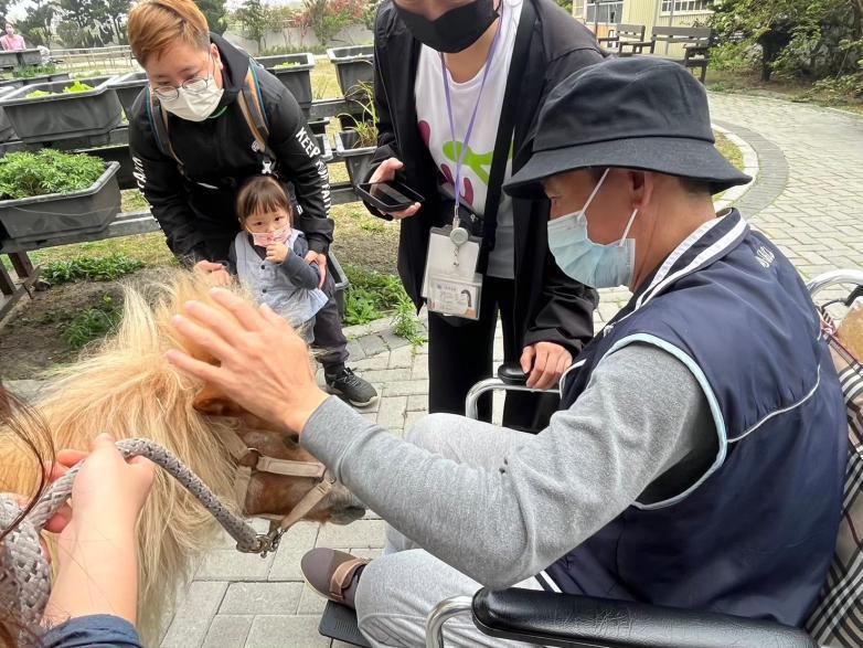 護家個案(信丞)親自教導小朋友如何從觸摸開始接觸與Blaze互動。（圖片來源／仁馨樂活園區）