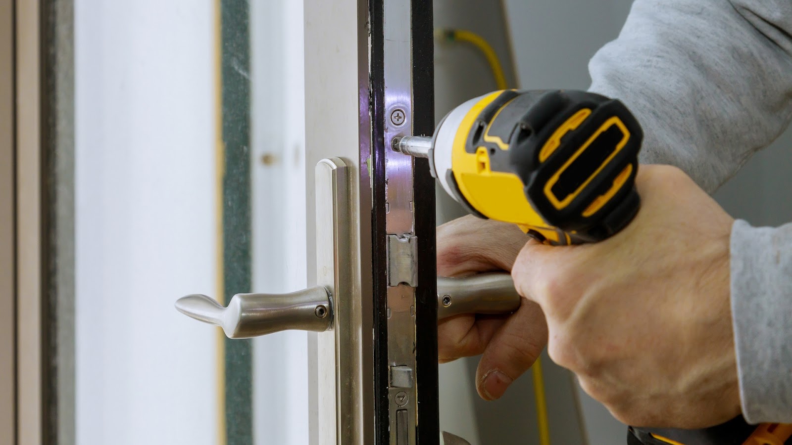 Using a power drill for lock installation on a modern residential door