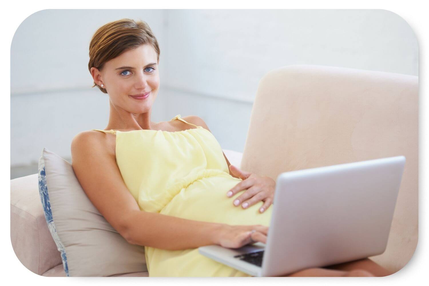 HIgh risk pregnant woman laying on the couch with a laptop on her lap