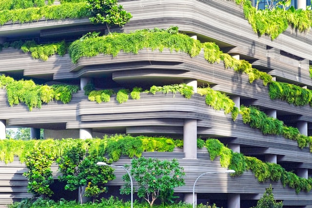 Grey building with projections jutting out with shrubs and plants hanging out