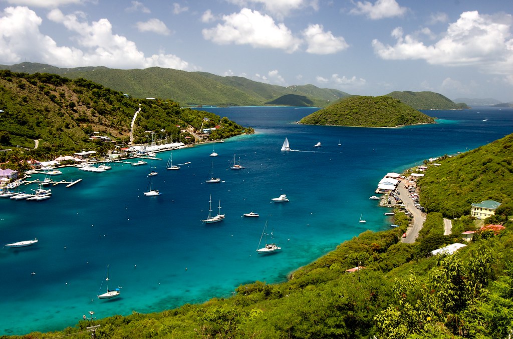 Boats gliding across a pretty lake, surrounded by lush green hills on The British Virgin Islands of Cali Colombia.
