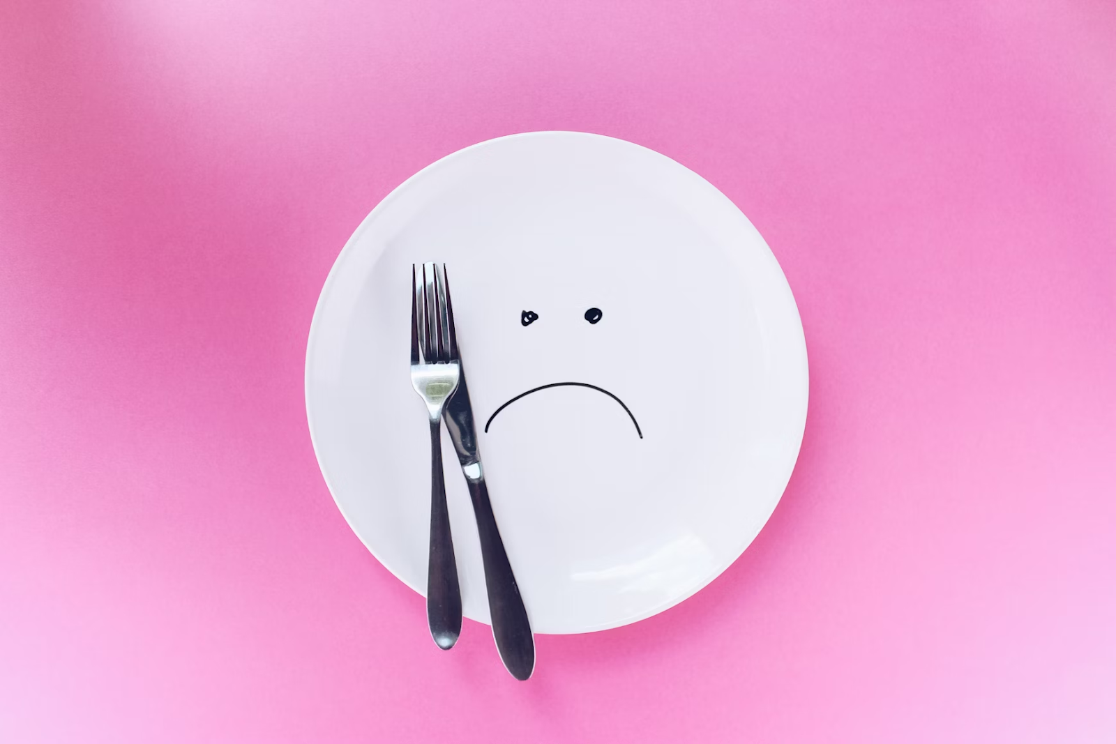 a plate with a face drawn on it and a fork and knife