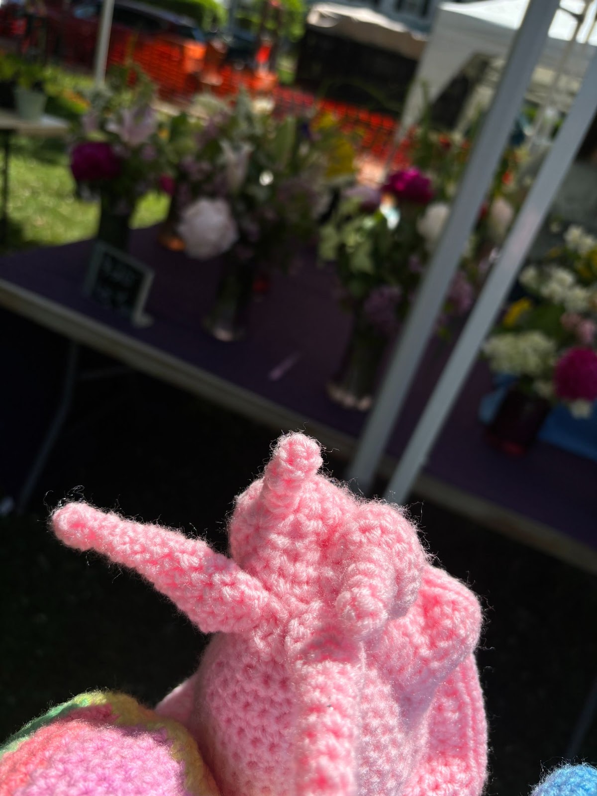 A pink snail in front of a flower stand