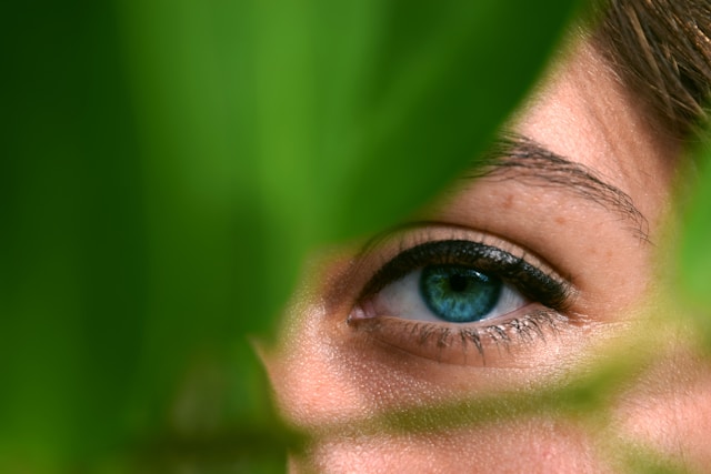 Woman's eyes peeking out from behind a leaf