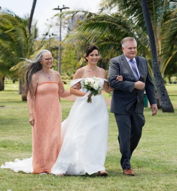 A person in a dress walking with a person in a suit

Description automatically generated