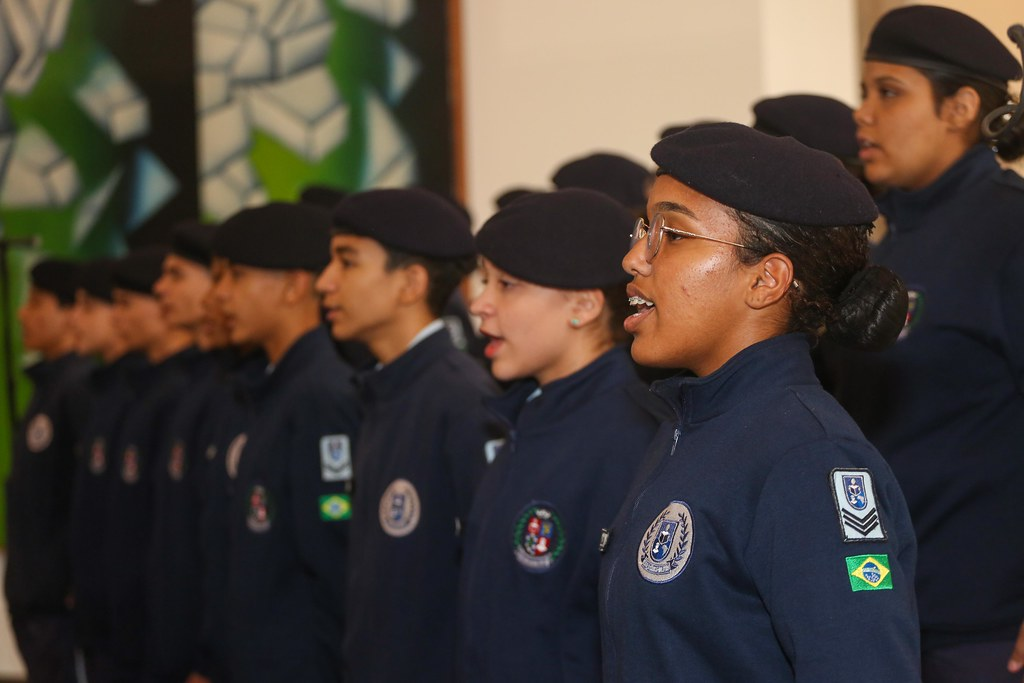 Jovens vestidos com roupas tradicionais de colégios militares cantam hino 