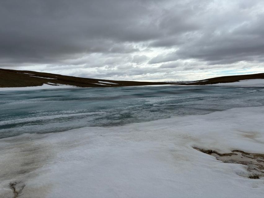 A frozen lake with snow and clouds

Description automatically generated