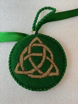 A green and gold embroidered medallion

Description automatically generated