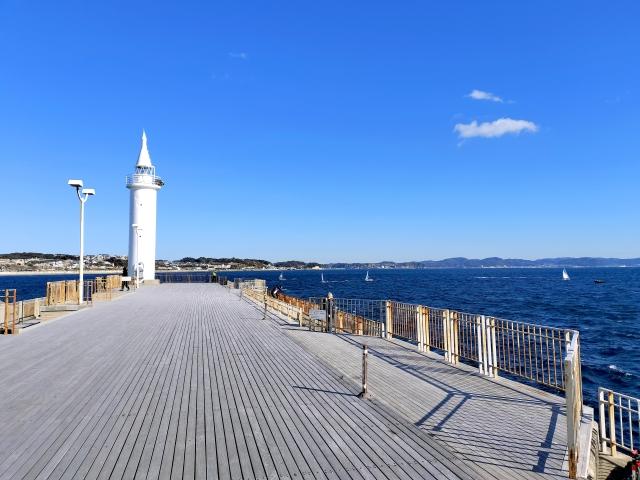 白い灯台がある海辺の写真。