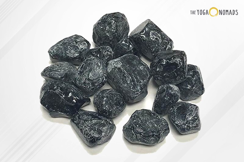  A collection of small, glossy, black stones known as Apache Tears. These stones are a type of volcanic glass, characterized by their smooth, rounded shapes and translucent quality when held up to the light.