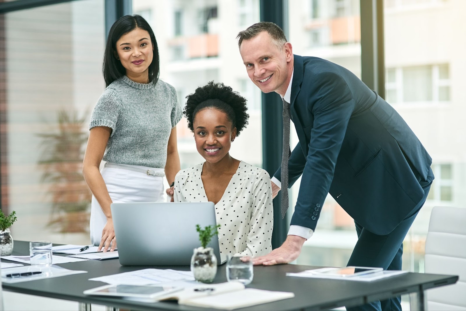 A cropped image of three business people gathered around the laptop. 