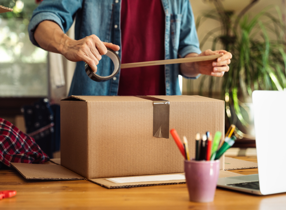 A man taping up a box of belongings for self storage.