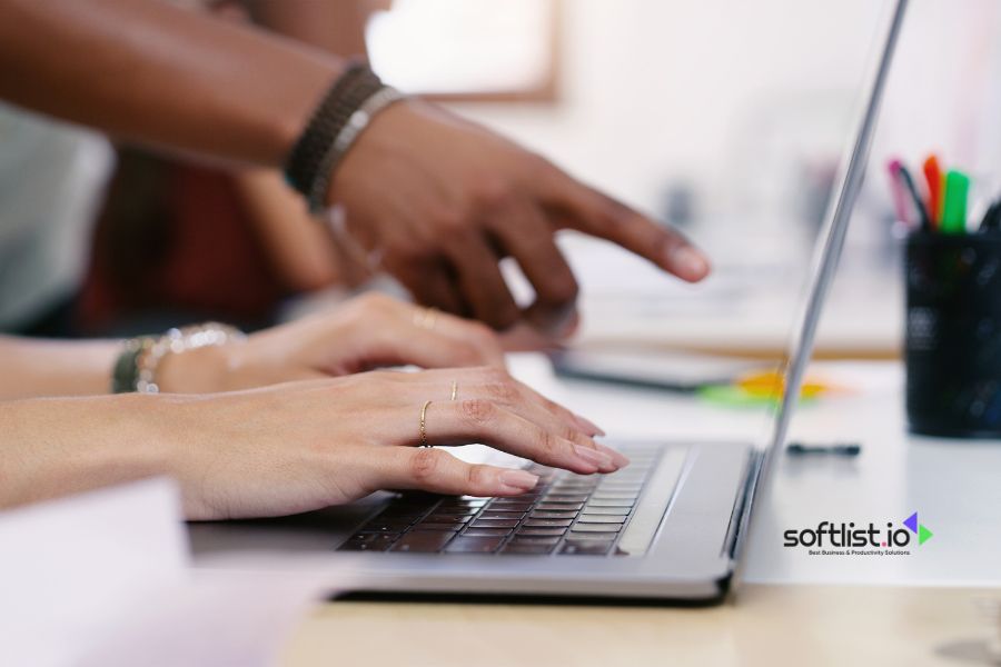 Hands typing on laptop, collaborating on business project with colleague.