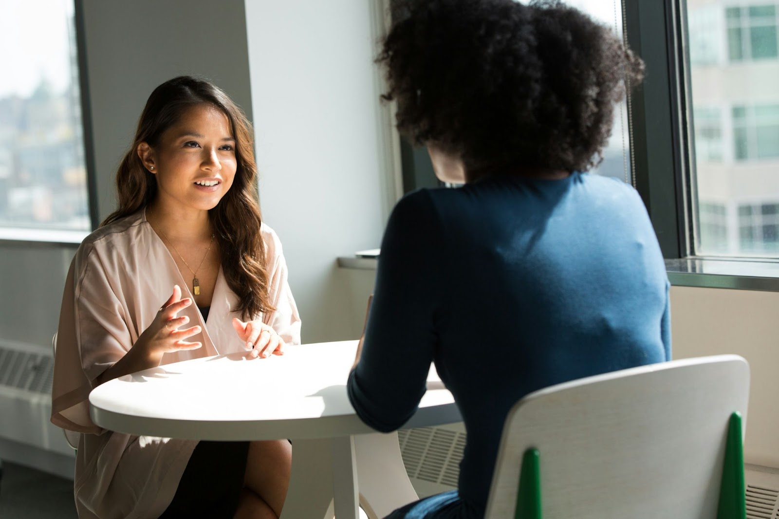Two people having a business meeting at a small table near a window.