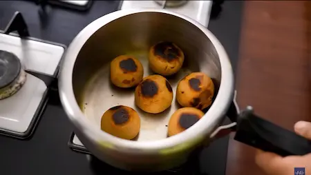 Stuffed littis being cooked in a greased pressure cooker without the whistle.