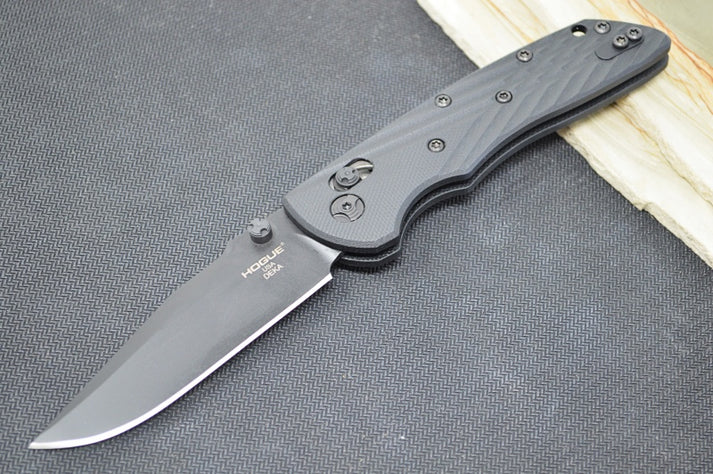 An image of the Hogue Deka, a folding knife equipped with an able-lock mechanism that securely locks the blade in place when deployed, on a simple black and wood background.