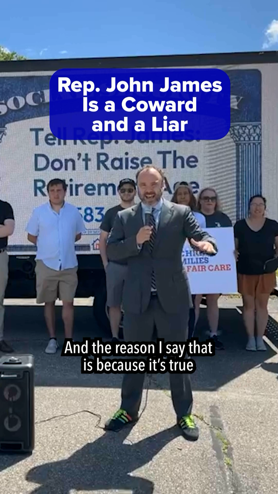 Picture of Alex standing in front of a billboard truck with text Rep. John James is a Coward and a Liar