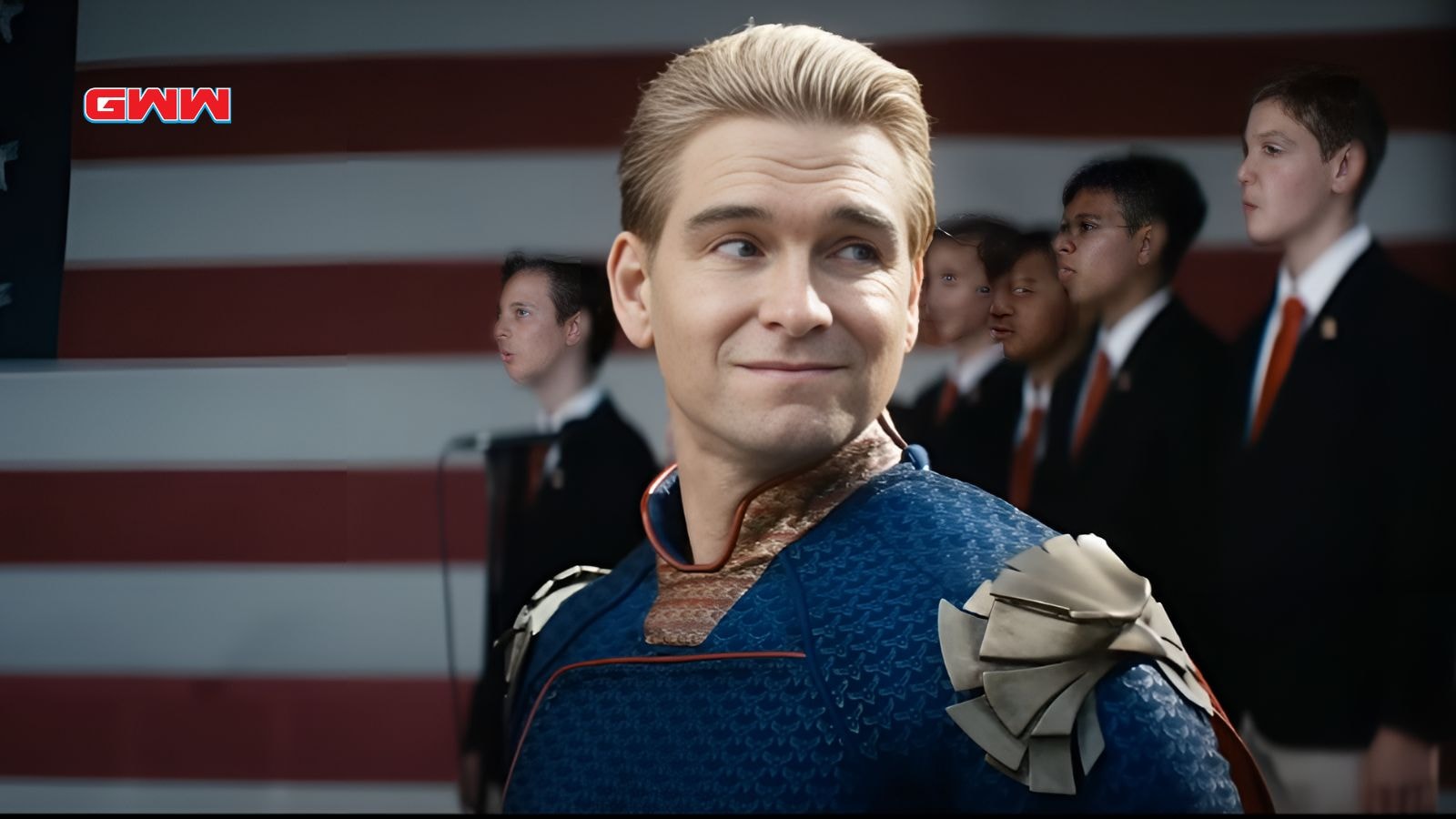 Smiling Homelander stands in front of an American flag background.