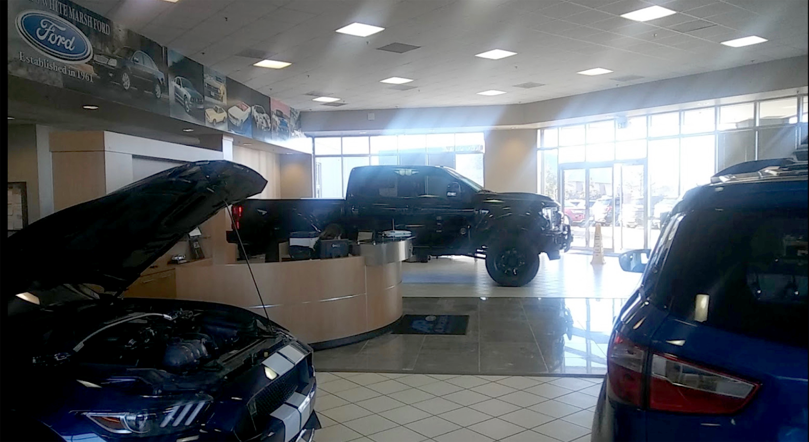 Inside view of a pre-engineered steel auto shop with cars and trucks on display in a bright, open showroom.