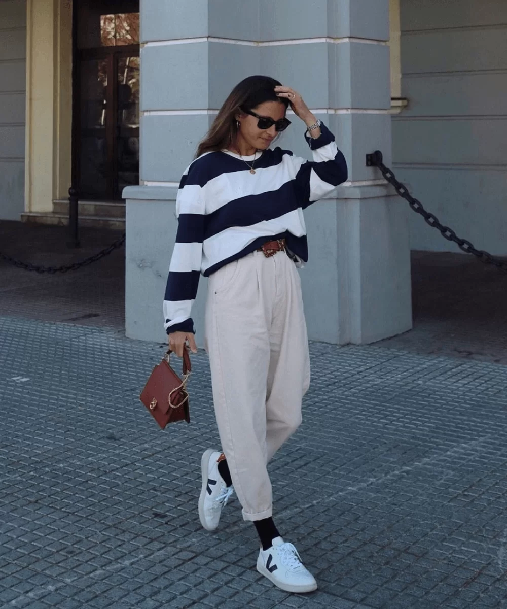 Mulher com calça e look casual, com tênis veja com detalhes pretos