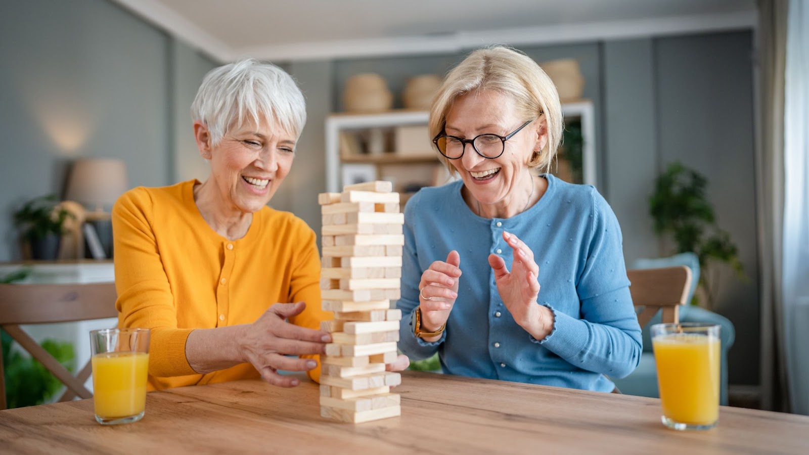 2 senior women socializing at an independent living community and playing Jenga together.