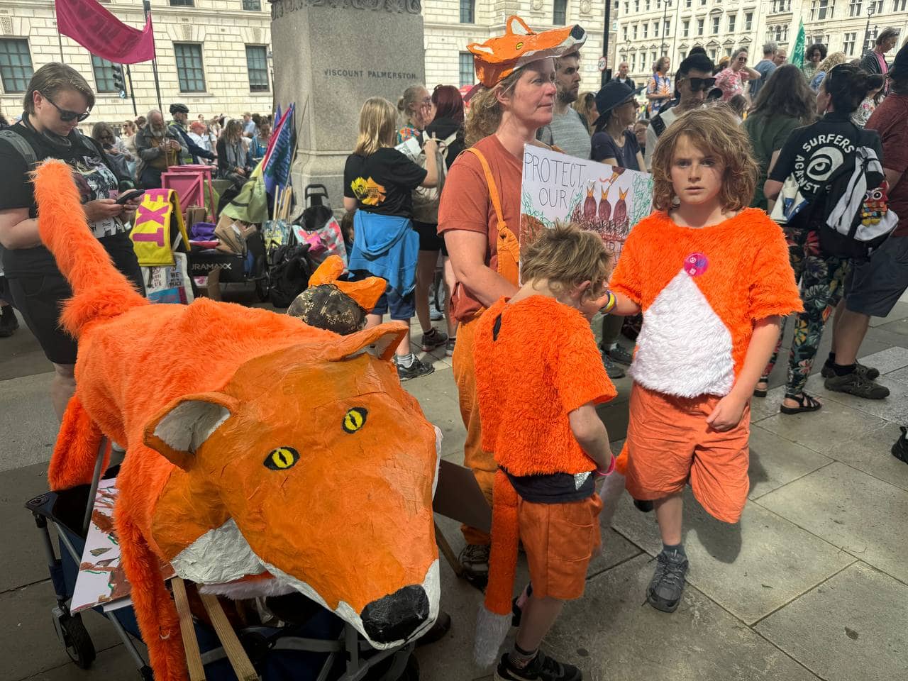 A mother and children dressed as foxes stand beside a giant fox sculpture