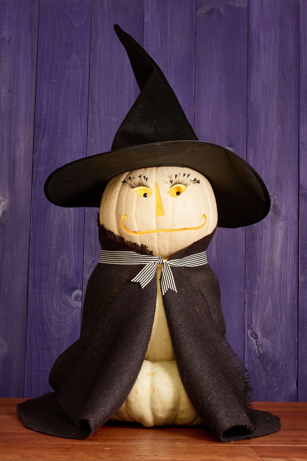 pumpkin carving ideas, three white pumpkins stacked on top of each other and carved to look like a witch with a black hat and coat