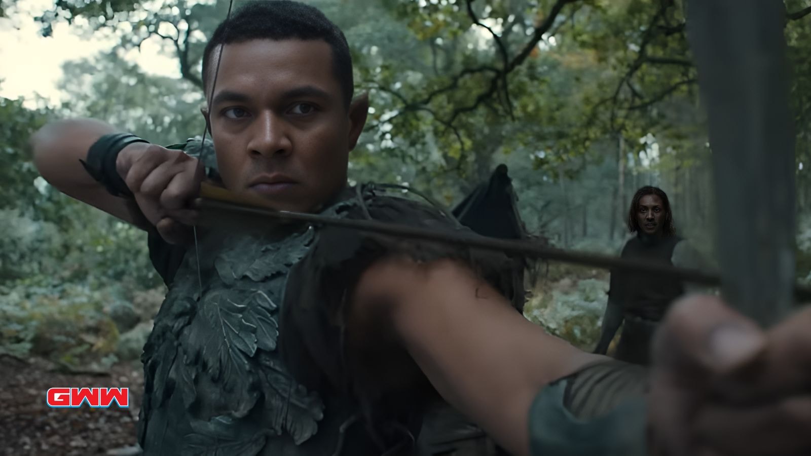 Arondir in a forest, aiming an arrow with determined expression.