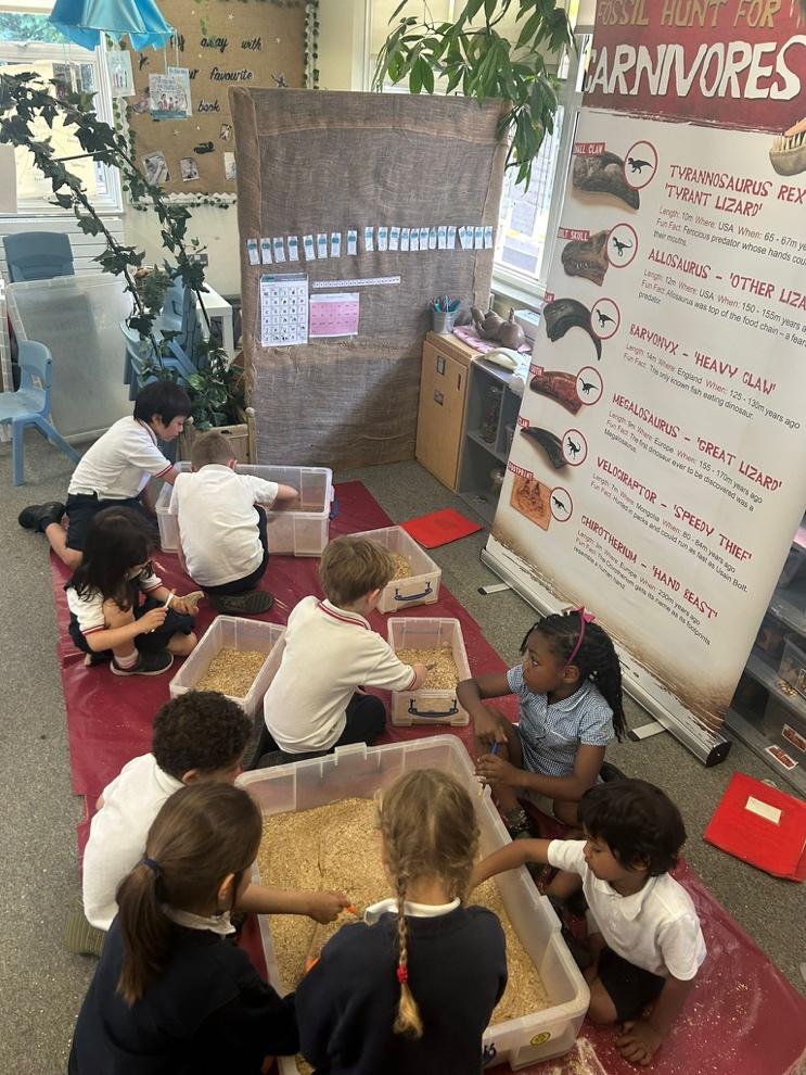 A group of children sitting on a red carpet

Description automatically generated