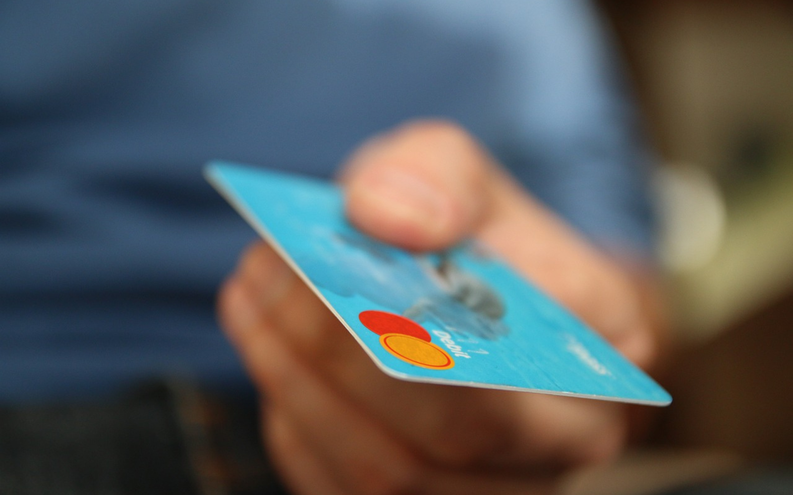 A person holding a credit cardDescription automatically generated