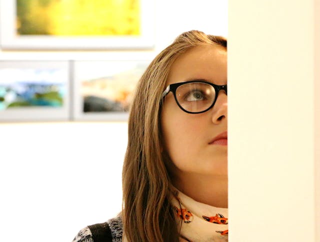 Young woman wearing glasses analyzing a picture.